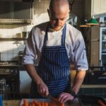 man slicing orange carrots